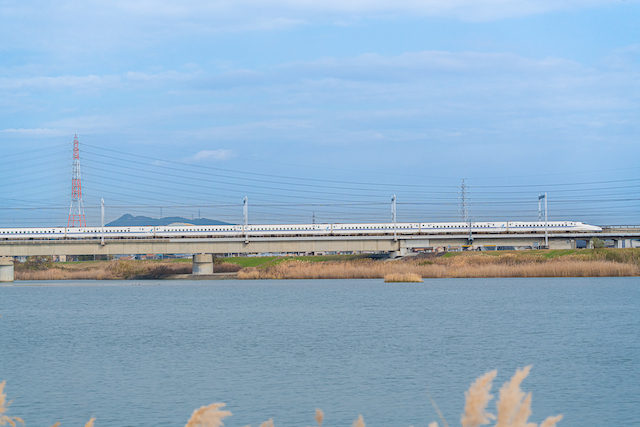 ２分割構図で新幹線を境にして加古川の川を、もう半分は青い空を撮って、真ん中に新幹線を走らせてみました。