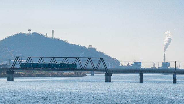 鉄の橋を渡る加古川線を走る電車の様子