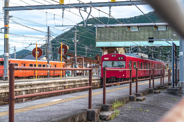 線路内の様子をフェンスの隙間から覗いてみると真っ赤な電車と少し色褪せた赤い電車が見えました